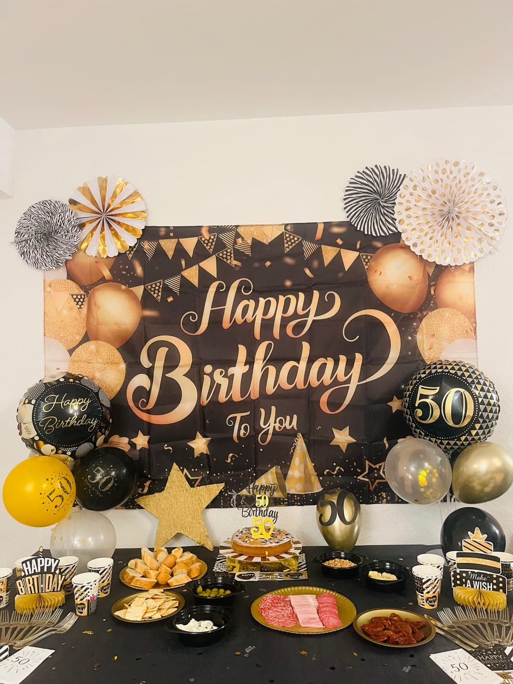 Party table dressed with balloons, paper fans, and a themed backdrop