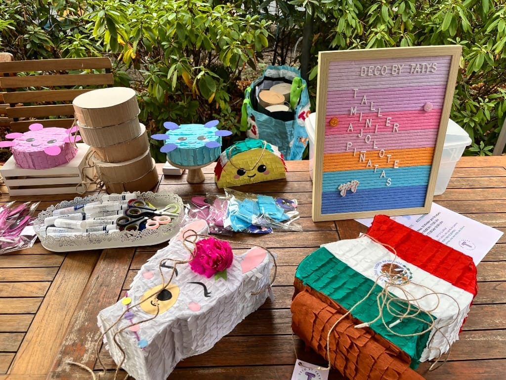 Finished handmade mini piñatas and craft supplies arranged on a wooden table